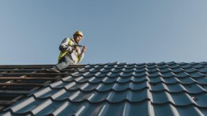 Construction worker installing metal roofing sheets under clear blue sky, demonstrating roofing safety and precision craftsmanship